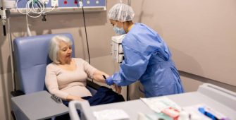 Nurse preparing a senior cancer patient for her chemotherapy at the hospital â medical treatment concepts